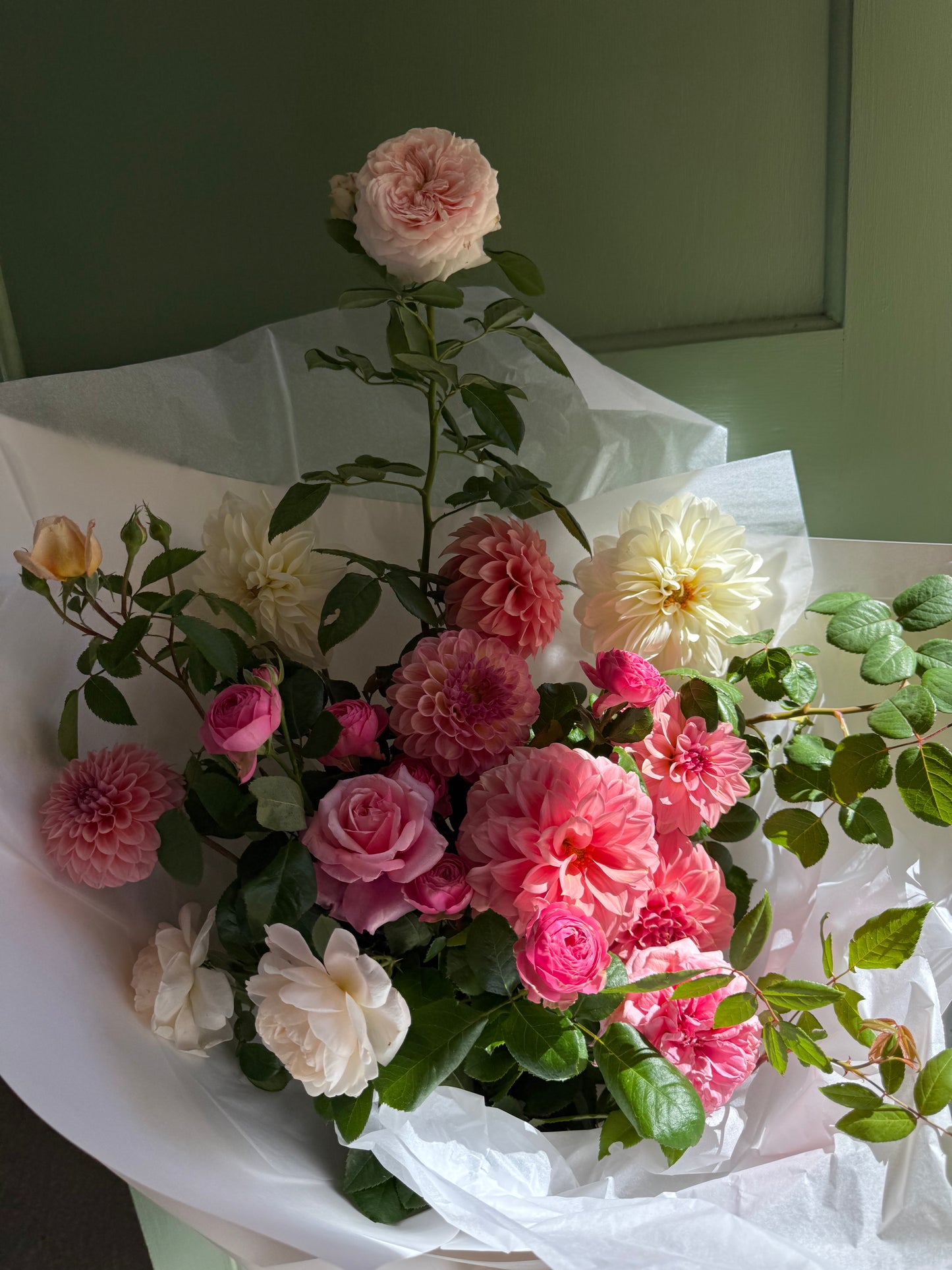 Bouquet of pink and white flowers with green leaves on a white background