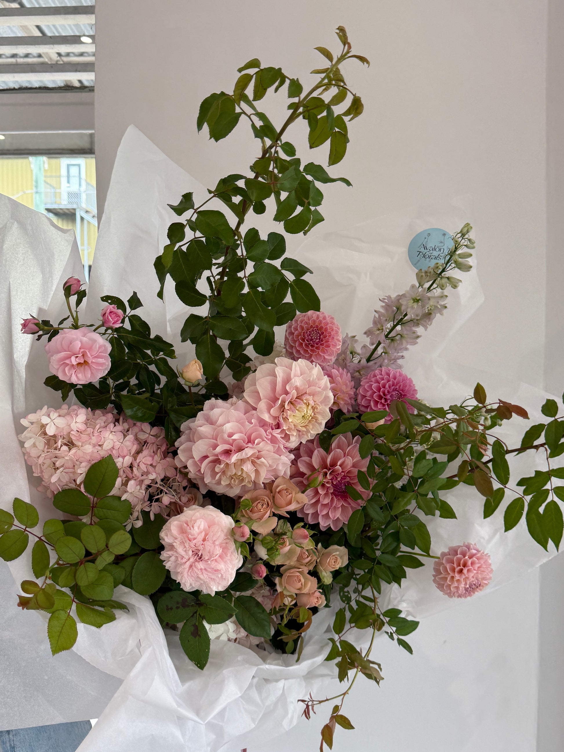 Bouquet of pink and green flowers wrapped in white paper on a light background