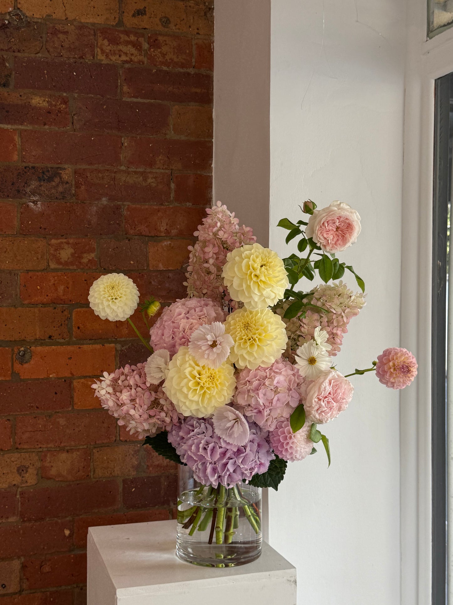 Bouquet of flowers on a brick surface with a white wall in the background