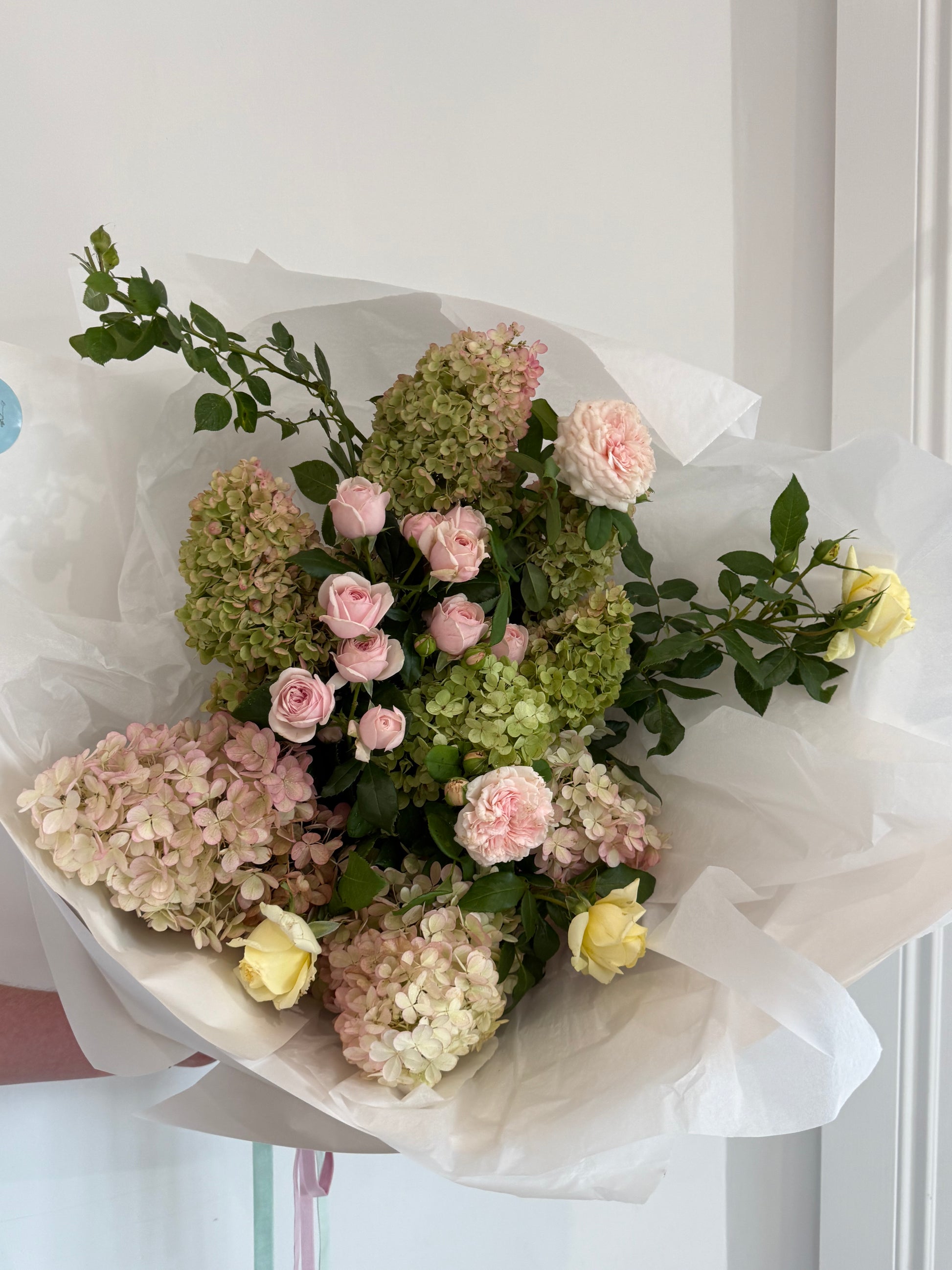 Bouquet of flowers wrapped in white paper on a light background